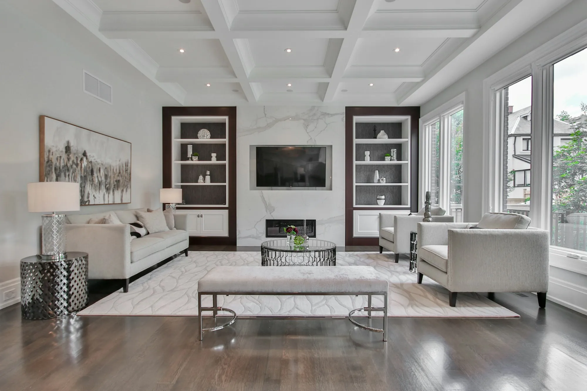 Living room with a coffered ceiling, built-in shelves and dark hardwood floors