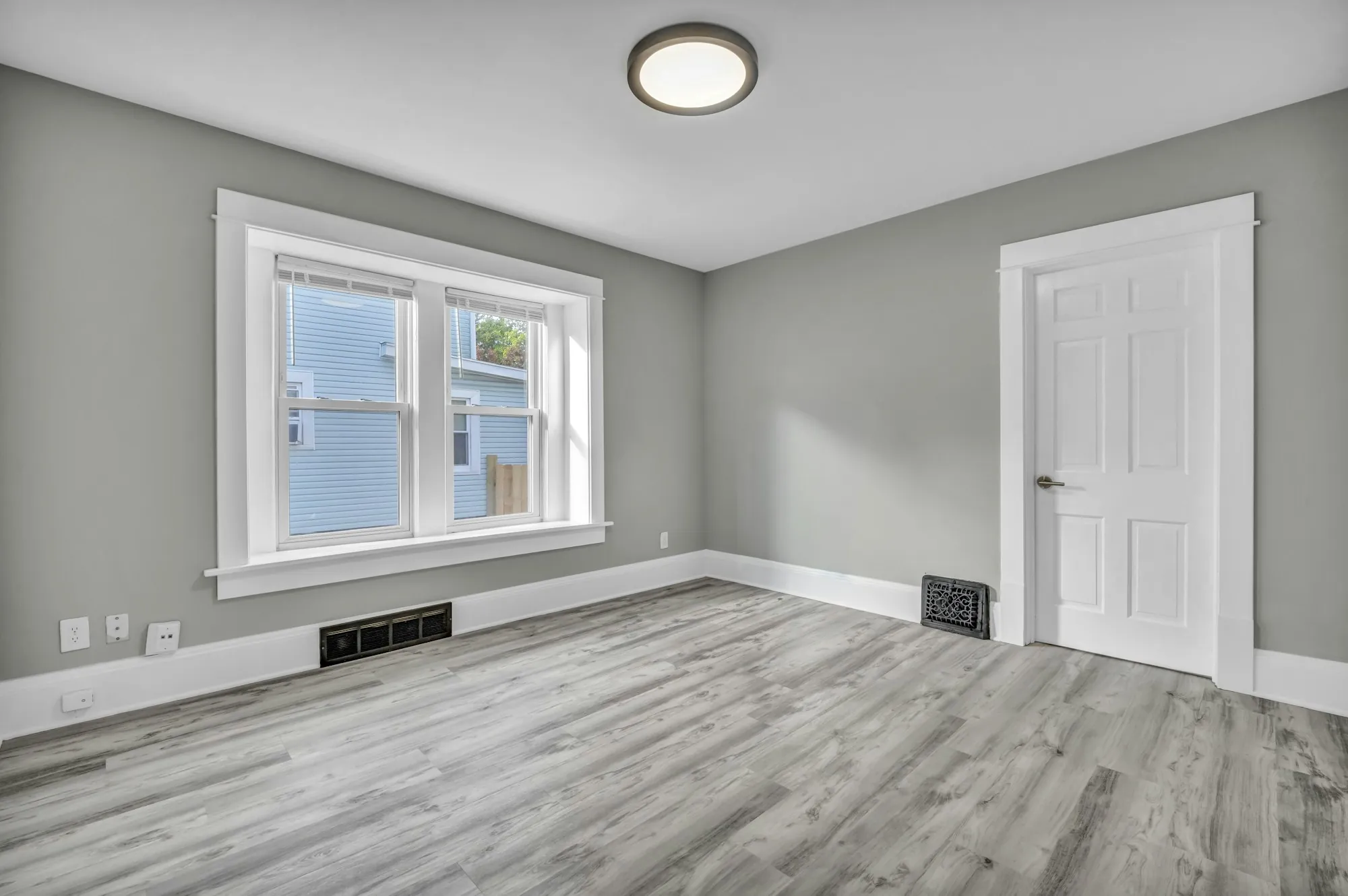 Empty room with freshly painted gray walls, white door and window trim