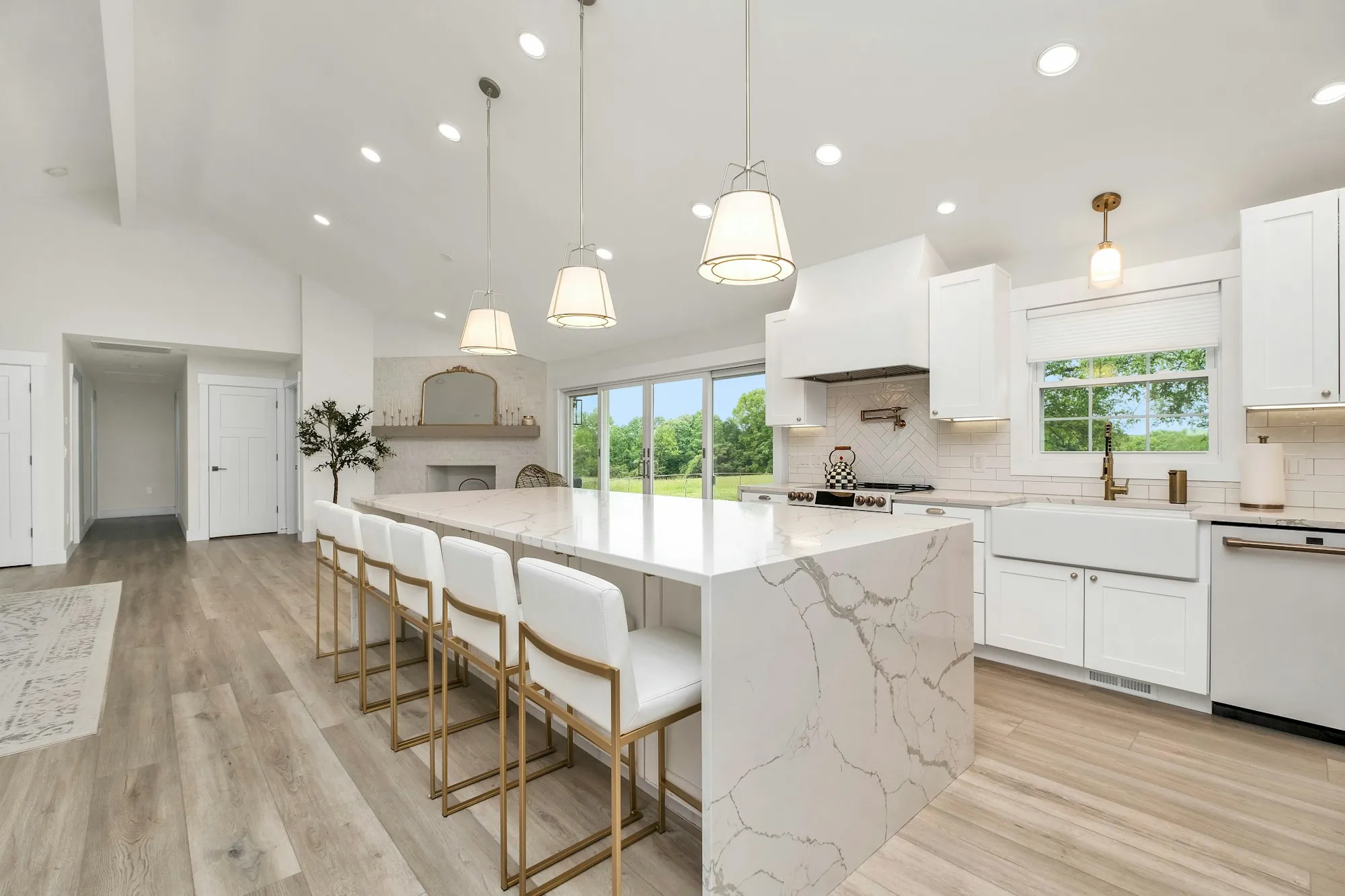 Bright kitchen with a marble waterfall island, pendant lights and white cabinets