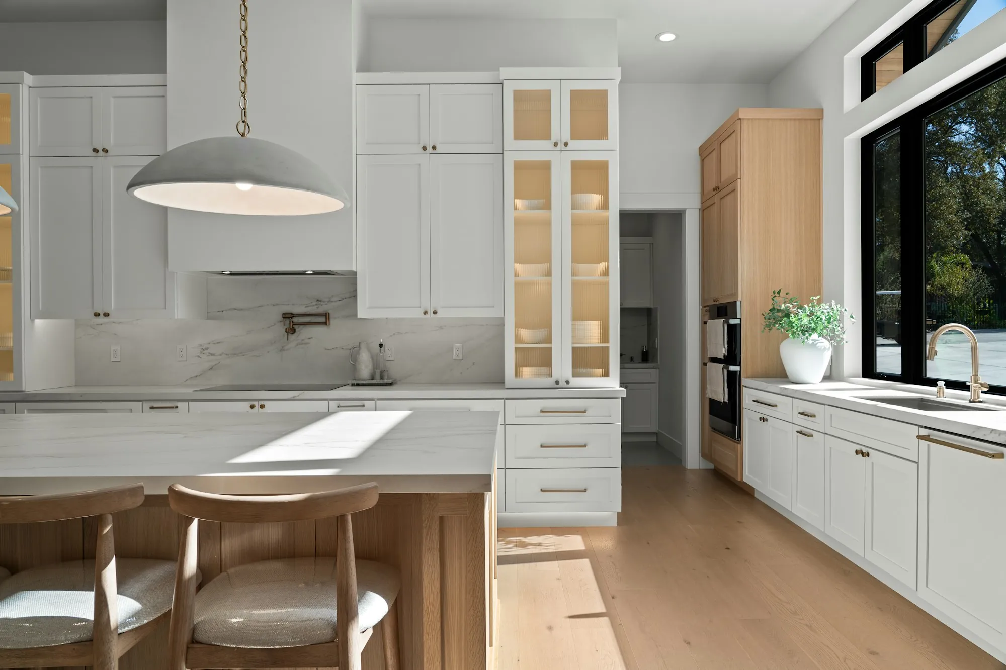 Remodeled kitchen with white shaker cabinets, a wood island and glass-front display cabinet