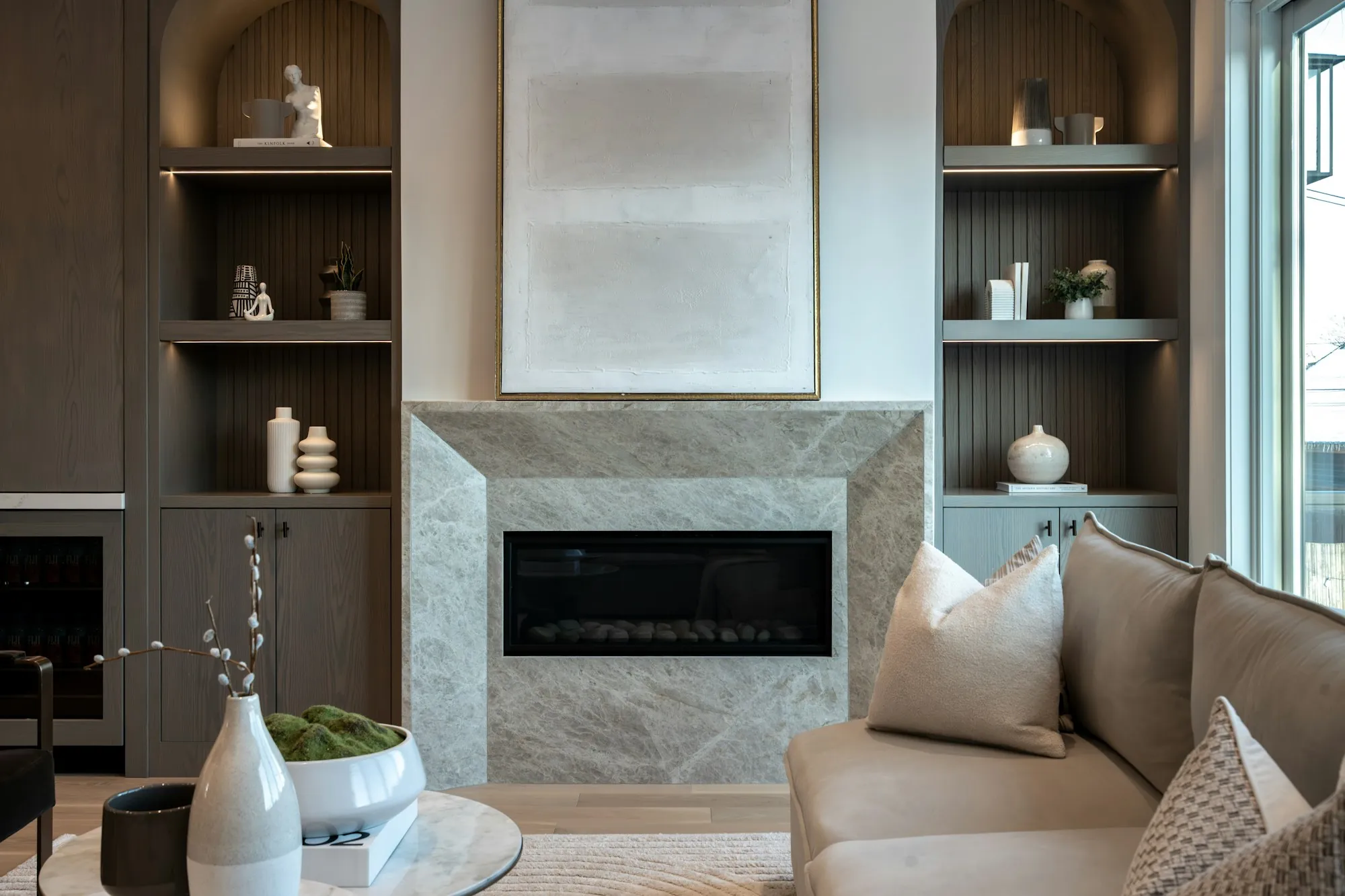 Living room with a stone fireplace surround and lit built-in shelving