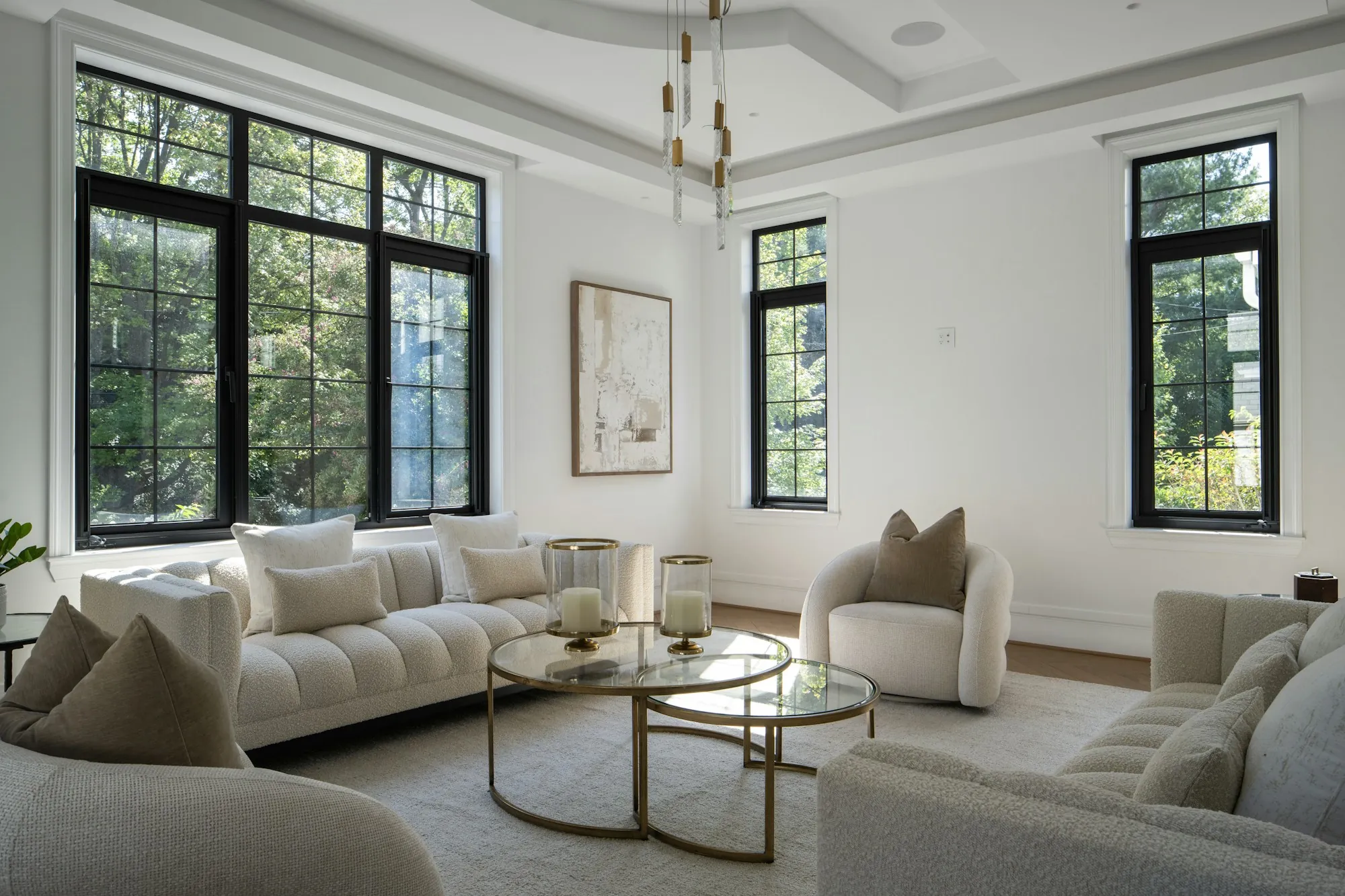 Renovated living room with black-framed windows, a tray ceiling and neutral furniture